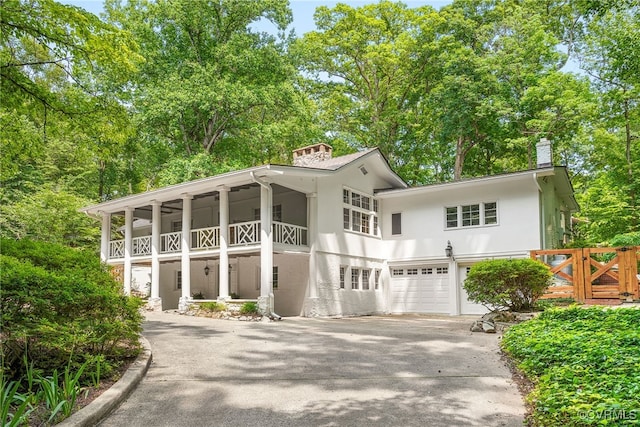 4103 Beechmont Rd, Richmond, VA 23235 - view of front of house featuring a chimney, stucco siding, asphalt driveway, a garage, and a balcony