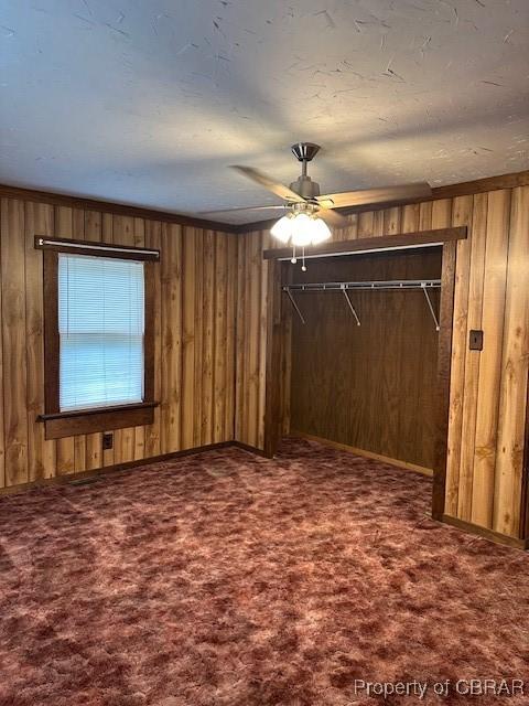 733 Holland Point Rd, Dutton, VA 23050 - unfurnished bedroom featuring carpet floors, wood walls, a closet, and a ceiling fan