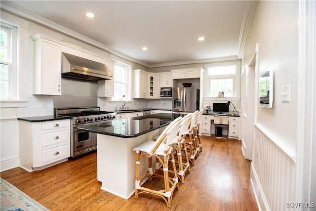 908 High St, Farmville, VA 23901 - kitchen with appliances with stainless steel finishes, wall chimney exhaust hood, crown molding, white cabinetry, and a breakfast bar area