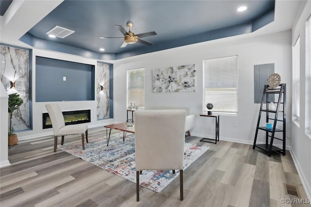 1114 Hinton St, Petersburg, VA 23803 - living room featuring ceiling fan, wood finished floors, a glass covered fireplace, baseboards, and a raised ceiling