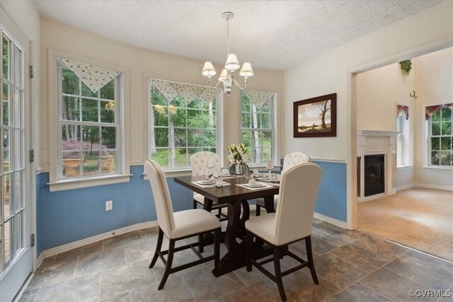 2024 Judes Ferry Rd, Powhatan, VA 23139 - dining area featuring a chandelier, a textured ceiling, dark stone finish floors, and a glass covered fireplace