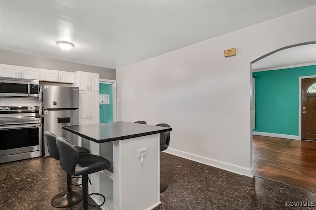 3304 Walnut St, Hopewell, VA 23860 - kitchen with appliances with stainless steel finishes, a breakfast bar area, white cabinets, dark countertops, and a kitchen island
