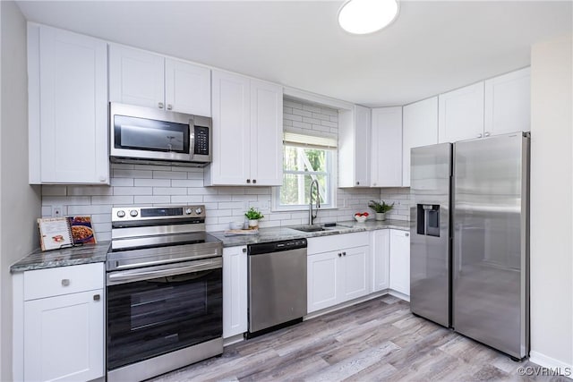 5007 Gention Rd, Chesterfield, VA 23832 - kitchen featuring appliances with stainless steel finishes, a sink, light wood-type flooring, white cabinetry, and decorative backsplash