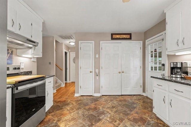 7503 Native Dancer Dr, Midlothian, VA 23112 - kitchen with electric range, under cabinet range hood, dark countertops, stone finish flooring, and white cabinets