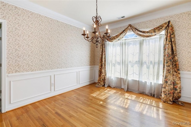 9401 Nolandwood Dr, Mechanicsville, VA 23116 - unfurnished dining area featuring wallpapered walls, a chandelier, a wainscoted wall, wood finished floors, and ornamental molding