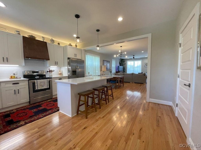 1710 N 29th St, Richmond, VA 23223 - kitchen with stainless steel appliances, extractor fan, a kitchen bar, light wood-style floors, and open floor plan