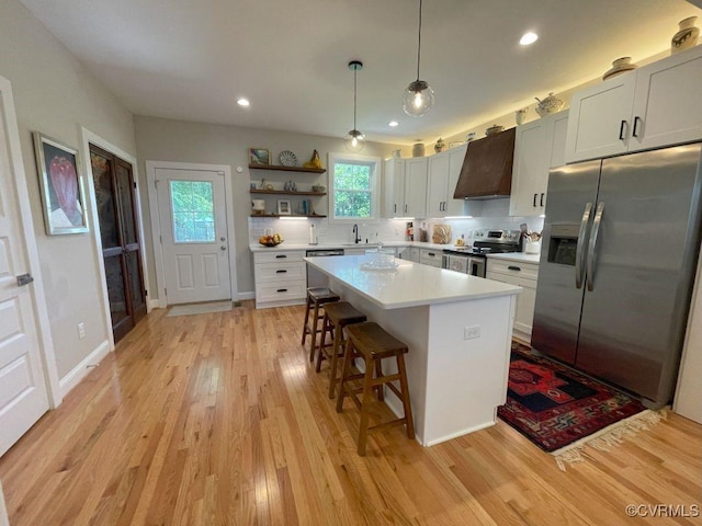 1710 N 29th St, Richmond, VA 23223 - kitchen featuring appliances with stainless steel finishes, custom range hood, open shelves, light wood-style flooring, and a breakfast bar area