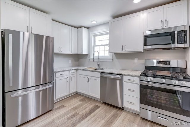 9019 Farmington Dr, Henrico, VA 23229 - kitchen with stainless steel appliances, a sink, white cabinets, light wood-style floors, and light stone counters