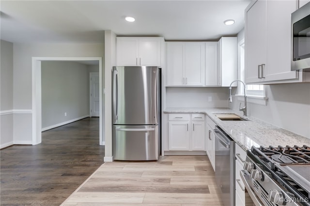 9019 Farmington Dr, Henrico, VA 23229 - kitchen featuring appliances with stainless steel finishes, a sink, light stone countertops, white cabinets, and light wood finished floors