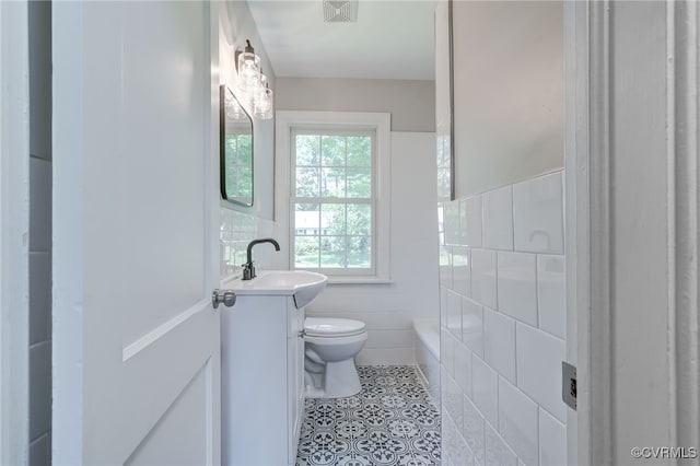 9019 Farmington Dr, Henrico, VA 23229 - bathroom featuring vanity, tile walls, toilet, tile patterned floors, and a bath