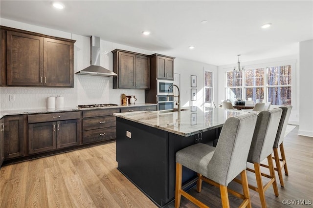 11183 Pinewild Dr, Providence Forge, VA 23140 - kitchen featuring wall chimney range hood, a kitchen bar, stainless steel appliances, backsplash, and light stone counters