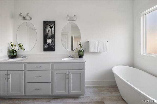 11183 Pinewild Dr, Providence Forge, VA 23140 - bathroom featuring double vanity, a freestanding tub, baseboards, and wood finished floors