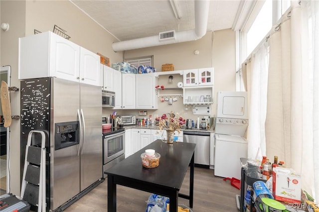 1701 W Leigh St, Richmond, VA 23220 - kitchen featuring appliances with stainless steel finishes, stacked washer / drying machine, white cabinets, wood finished floors, and open shelves