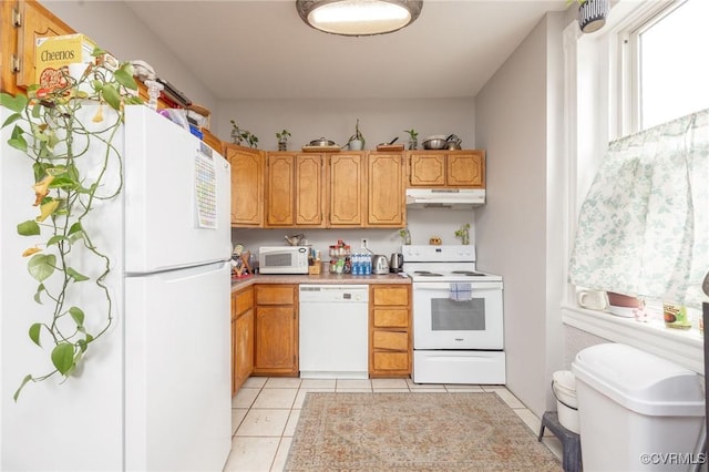 1701 W Leigh St, Richmond, VA 23220 - kitchen with white appliances, under cabinet range hood, light tile patterned floors, light countertops, and brown cabinets