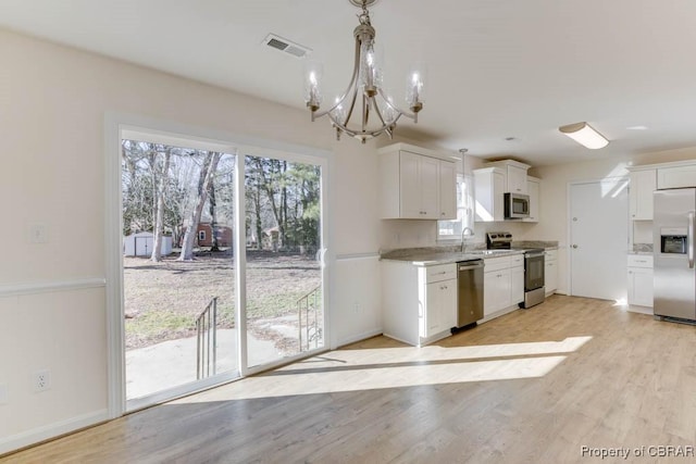 525 Helm Dr, Newport News, VA 23602 - kitchen with stainless steel appliances, a chandelier, a sink, white cabinetry, and light wood-style floors