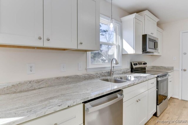 525 Helm Dr, Newport News, VA 23602 - kitchen featuring stainless steel appliances, a sink, white cabinetry, light wood finished floors, and light stone countertops
