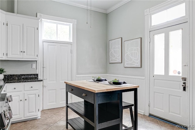 2210 Stuart Ave, Richmond, VA 23220 - kitchen with stainless steel stove, wood counters, white cabinetry, crown molding, and a wainscoted wall
