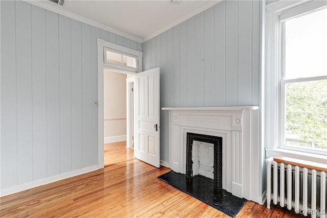 2210 Stuart Ave, Richmond, VA 23220 - unfurnished living room with radiator heating unit, ornamental molding, wood finished floors, a fireplace with raised hearth, and baseboards