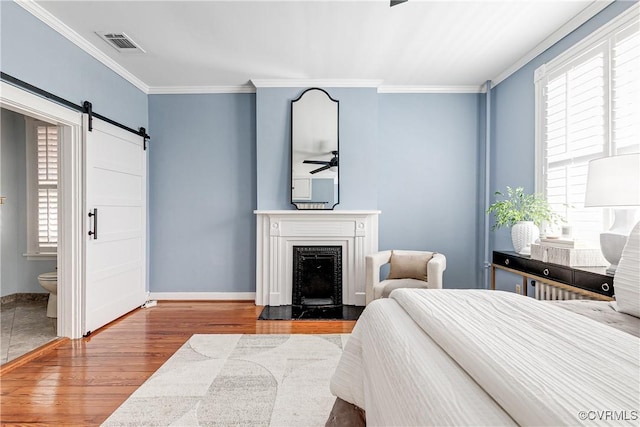 2210 Stuart Ave, Richmond, VA 23220 - bedroom featuring wood finished floors, crown molding, a barn door, baseboards, and a premium fireplace