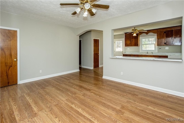 11512 Duncan Rd, Dinwiddie, VA 23805 - unfurnished living room featuring ceiling fan, arched walkways, a textured ceiling, light wood-type flooring, and a sink