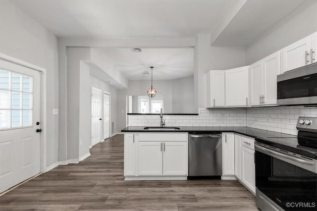 1317 N 22nd St, Richmond, VA 23223 - kitchen featuring appliances with stainless steel finishes, dark countertops, a peninsula, and decorative backsplash