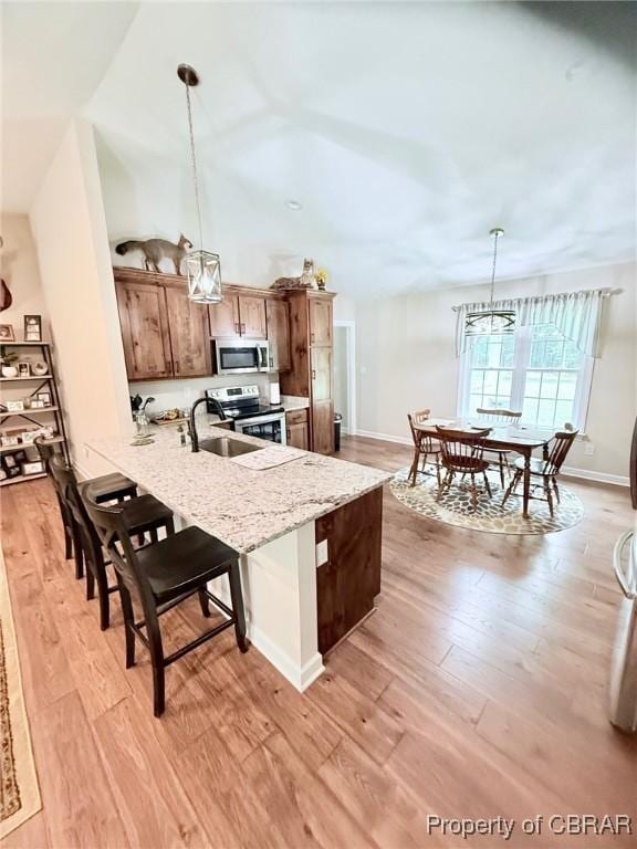 1205 Trimmers Shop Rd, West Point, VA 23181 - kitchen with stainless steel appliances, a sink, light wood finished floors, a peninsula, and a kitchen breakfast bar