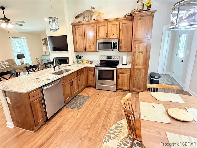 1205 Trimmers Shop Rd, West Point, VA 23181 - kitchen featuring stainless steel appliances, a sink, light wood finished floors, a peninsula, and brown cabinetry