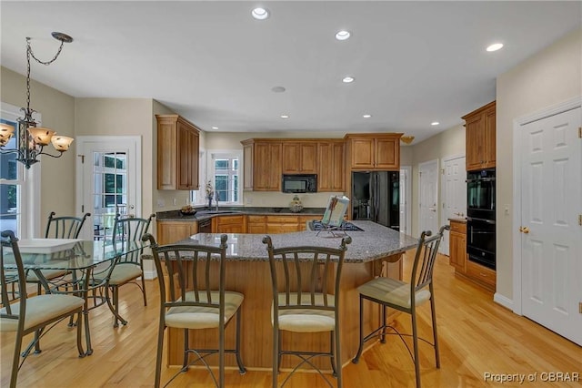 1708 Centennial Dr, Toano, VA 23168 - kitchen featuring black appliances, light wood finished floors, a breakfast bar area, a chandelier, and brown cabinetry