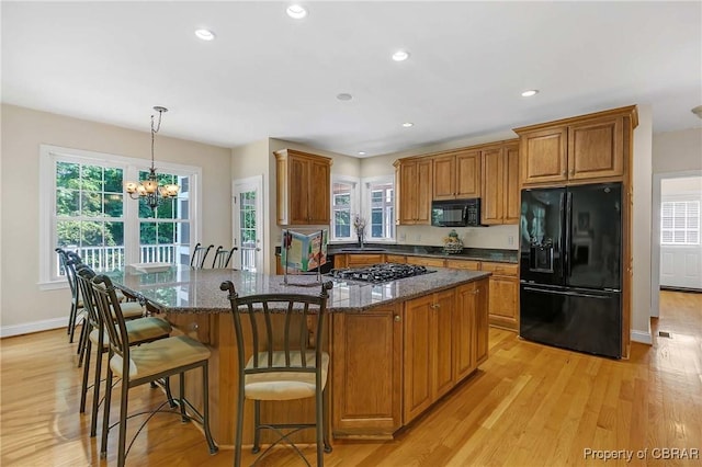1708 Centennial Dr, Toano, VA 23168 - kitchen with black appliances, brown cabinetry, light wood-style floors, a kitchen island, and healthy amount of natural light
