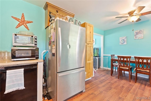 7143 Cherry Ln, Mechanicsville, VA 23111 - kitchen with freestanding refrigerator, black microwave, wine cooler, light wood-style flooring, and a ceiling fan