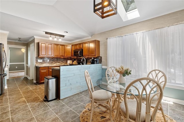 12912 Cottage Mill Pl, Midlothian, VA 23114 - kitchen featuring appliances with stainless steel finishes, brown cabinetry, lofted ceiling, a skylight, and baseboards