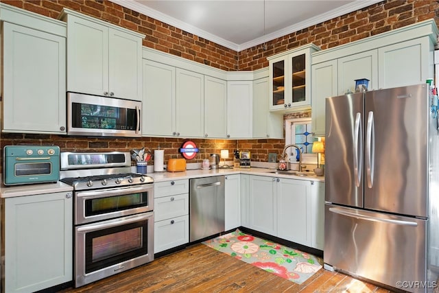323 N 27th St, Richmond, VA 23223 - kitchen featuring stainless steel appliances, crown molding, light countertops, wood finished floors, and glass insert cabinets