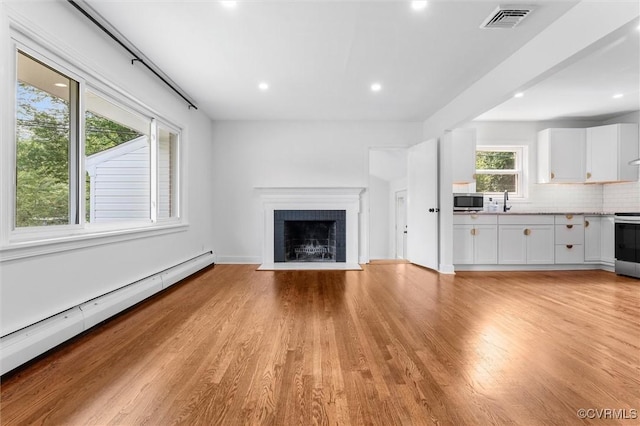 602 Trellis Ln, Henrico, VA 23075 - unfurnished living room featuring baseboard heating, light wood-style flooring, a fireplace with flush hearth, recessed lighting, and a sink