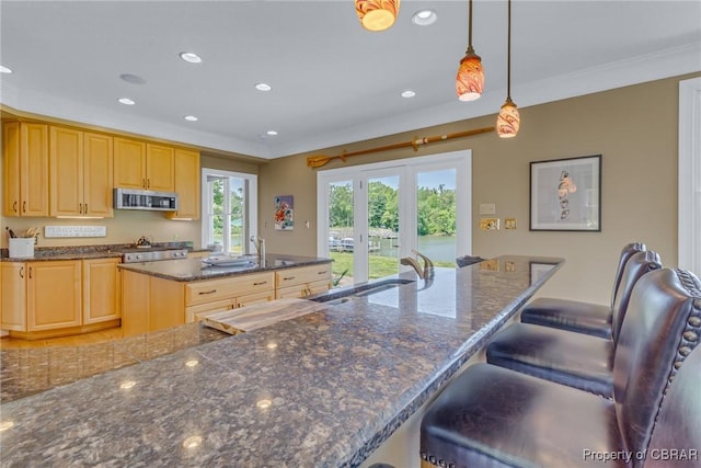 241 Tranquility Rd, Reedville, VA 22539 - kitchen featuring stainless steel microwave, light brown cabinetry, recessed lighting, a kitchen island, and a breakfast bar