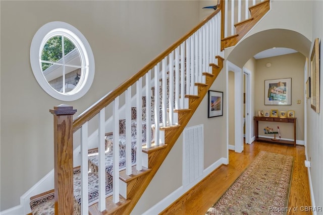 241 Tranquility Rd, Reedville, VA 22539 - stairway with wood finished floors, arched walkways, a towering ceiling, and baseboards