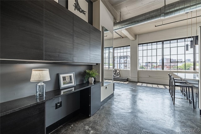 101 W Marshall St Unit U47, Richmond, VA 23220 - kitchen with modern cabinets, concrete flooring, dark cabinetry, beam ceiling, and dark stone countertops