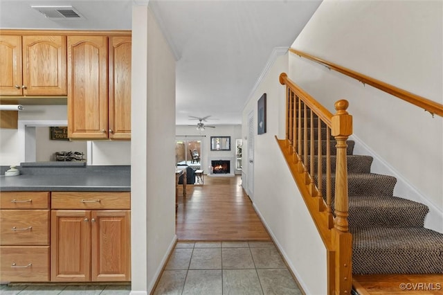11605 E Briar Patch Dr, Midlothian, VA 23113 - kitchen with a warm lit fireplace, dark countertops, a ceiling fan, light tile patterned floors, and baseboards