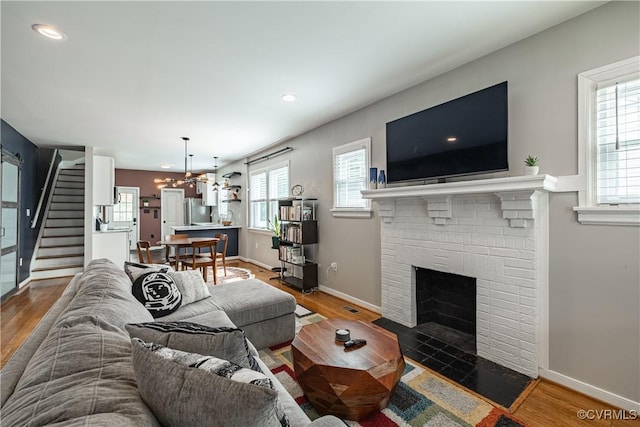 1815 Seddon Rd, Richmond, VA 23227 - living area featuring stairs, wood finished floors, a brick fireplace, recessed lighting, and a chandelier