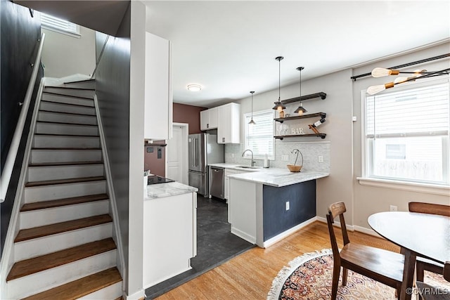 1815 Seddon Rd, Richmond, VA 23227 - kitchen with appliances with stainless steel finishes, a peninsula, white cabinetry, light wood finished floors, and backsplash