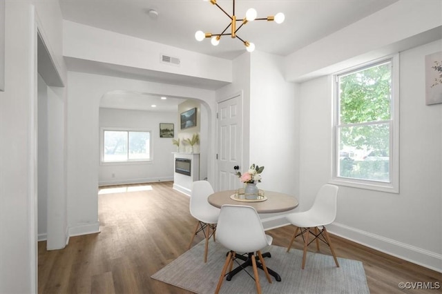 215 S S St, Petersburg, VA 23803 - dining area featuring a glass covered fireplace, arched walkways, a chandelier, wood finished floors, and baseboards