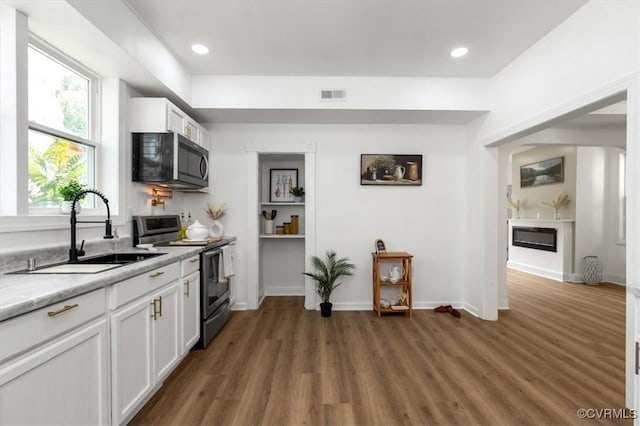 215 S S St, Petersburg, VA 23803 - kitchen with appliances with stainless steel finishes, a sink, light countertops, wood finished floors, and white cabinets