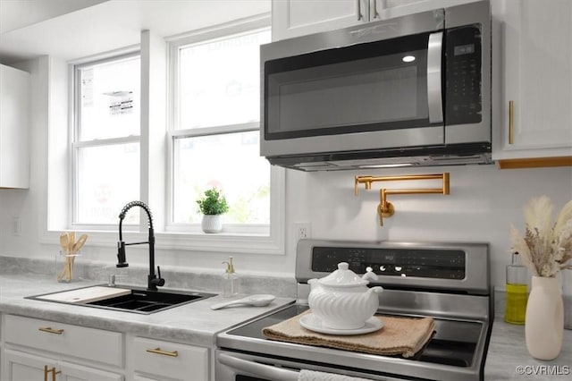 215 S S St, Petersburg, VA 23803 - kitchen with appliances with stainless steel finishes, a sink, white cabinets, and plenty of natural light