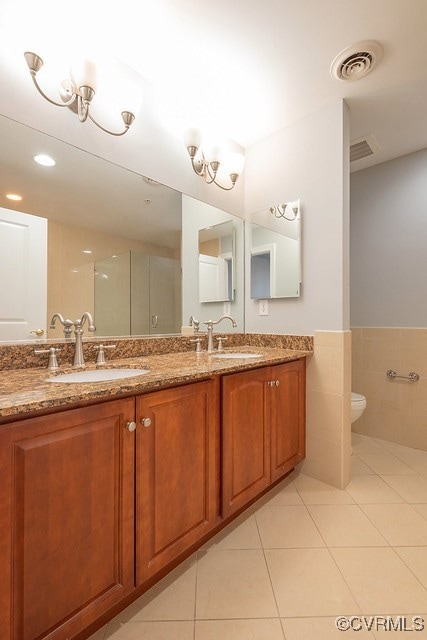 6 N 6th St Unit U3C, Richmond, VA 23219 - full bathroom featuring tile patterned flooring, double vanity, tile walls, a wainscoted wall, and toilet
