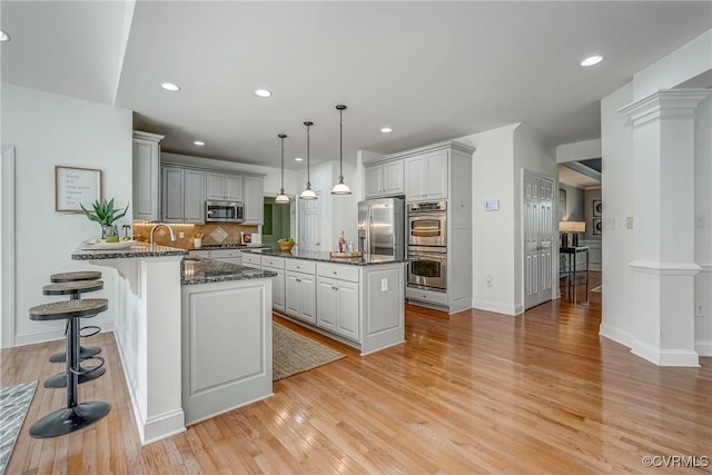 4307 Wilcot Dr, Midlothian, VA 23113 - kitchen with stainless steel appliances, a peninsula, dark stone counters, decorative backsplash, and light wood finished floors