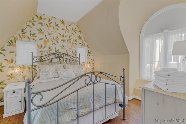 1083 Ottoman Ferry Rd, Mollusk, VA 22503 - bedroom featuring vaulted ceiling, wallpapered walls, wood finished floors, and baseboards