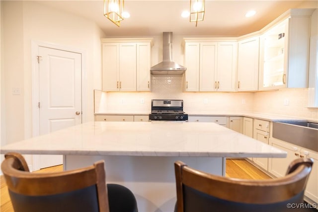 12194 Elnora Ln, Glen Allen, VA 23059 - kitchen featuring wall chimney exhaust hood, stainless steel gas range oven, a breakfast bar area, decorative backsplash, and recessed lighting