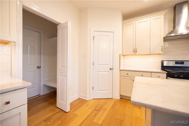 12194 Elnora Ln, Glen Allen, VA 23059 - kitchen with wall chimney range hood, stainless steel gas range, light wood finished floors, decorative backsplash, and white cabinetry
