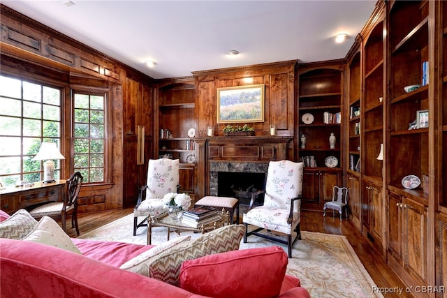 1921 Miln House Rd, Williamsburg, VA 23185 - living area featuring built in features, wood walls, wood finished floors, a premium fireplace, and ornamental molding