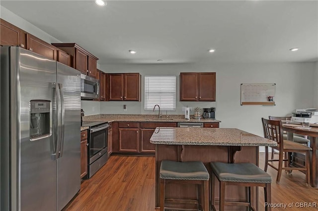 202 Arbordale Loop, Williamsburg, VA 23188 - kitchen featuring stainless steel appliances, a breakfast bar area, dark wood finished floors, a sink, and light stone countertops