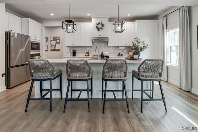 18342 Magnolia Run Ln, Moseley, VA 23120 - kitchen featuring freestanding refrigerator, black microwave, under cabinet range hood, light countertops, and a kitchen island with sink